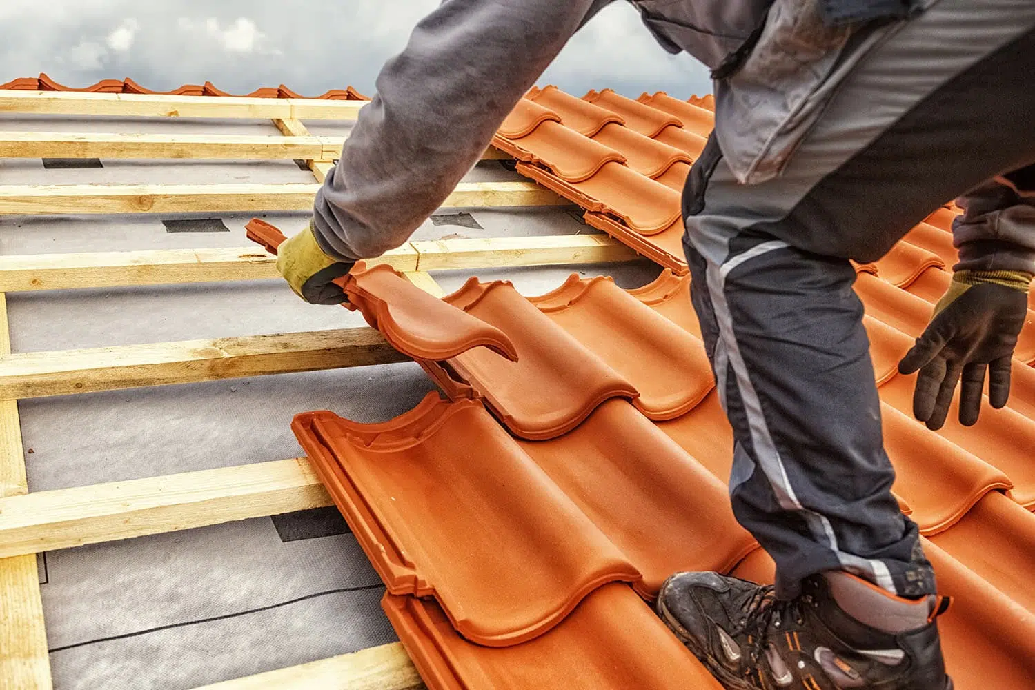 Close-up of a roofer installing orange clay tiles during a Roofing Replacement Brentwood TN project by Burish Builders TN.